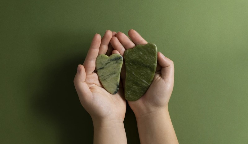 Top view hands holding green gua sha